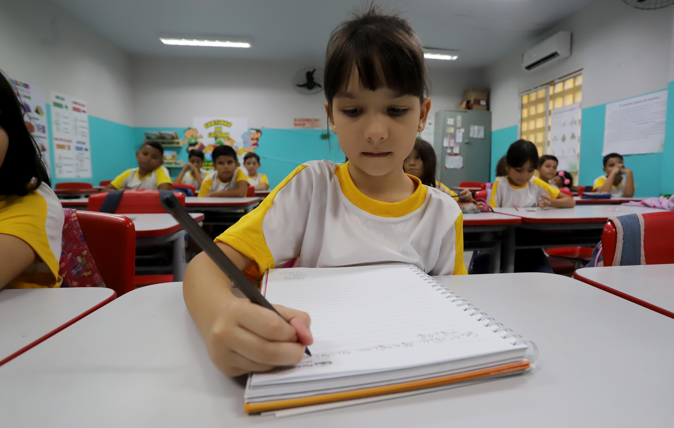 criança lendo um livro em sala de aula